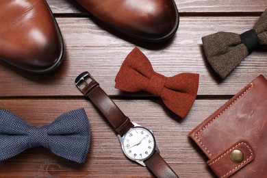 Photo of Stylish color bow ties, shoes, wallet and wristwatch on wooden background, flat lay