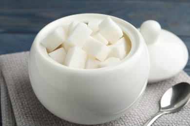 Photo of Refined sugar cubes in ceramic bowl on table, closeup