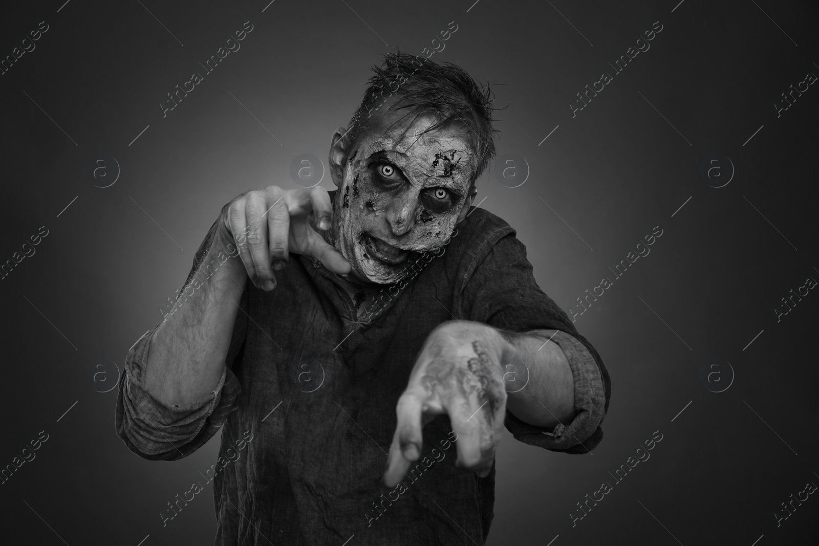 Photo of Scary zombie on dark background, black and white effect. Halloween monster