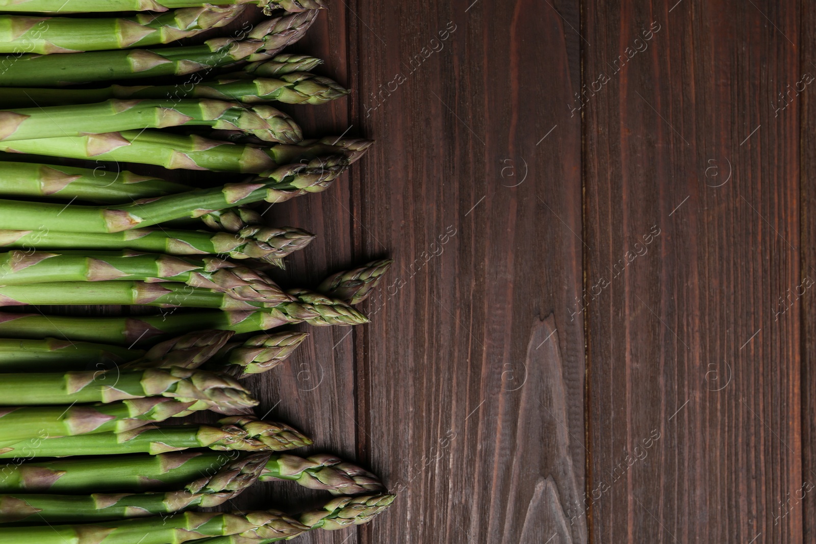 Photo of Fresh raw asparagus on wooden table, flat lay. Space for text