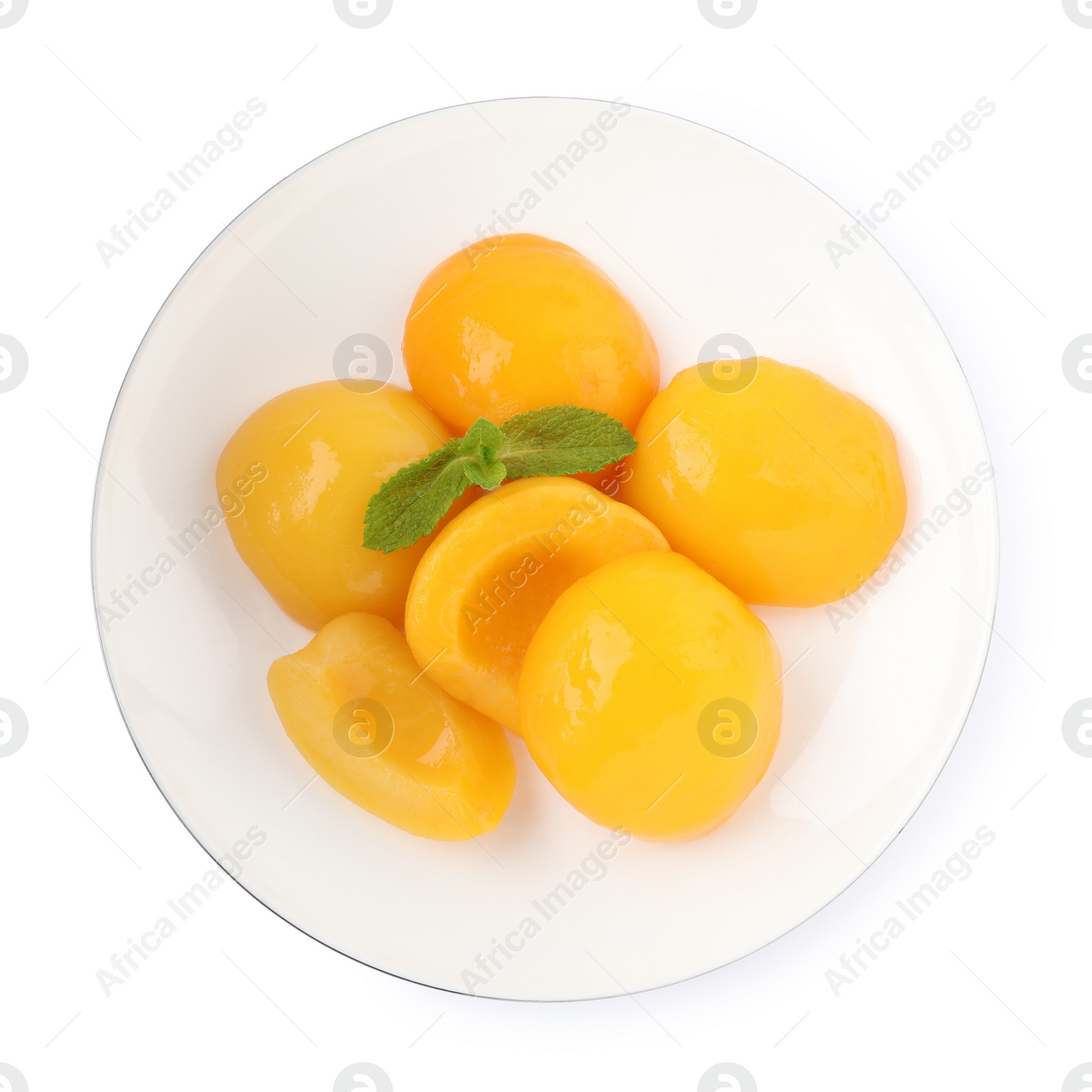 Photo of Halves of canned peaches with mint leaves isolated on white, top view