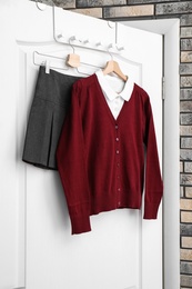 Photo of School uniform for girl hanging on white door