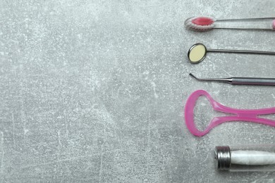 Photo of Tongue cleaner, toothbrush, dental floss and dentist instruments on grey background, flat lay. Space for text