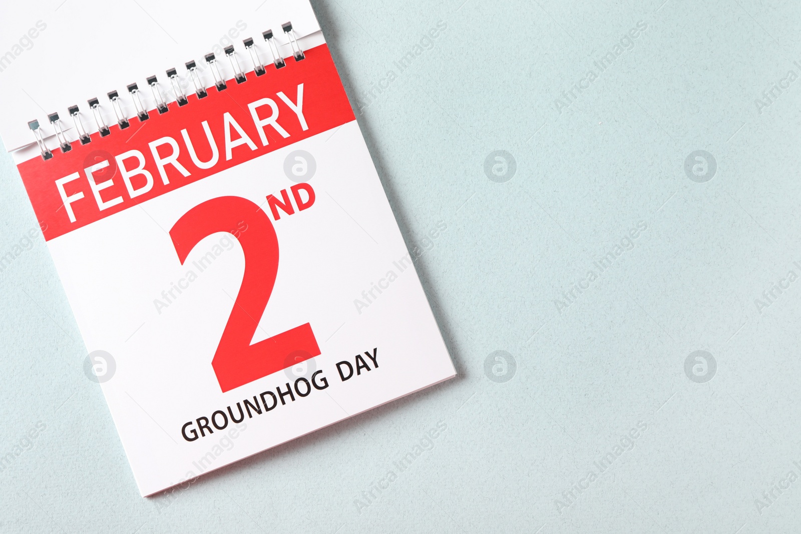 Photo of Top view of calendar with date February 2nd on light background, space for text. Groundhog day