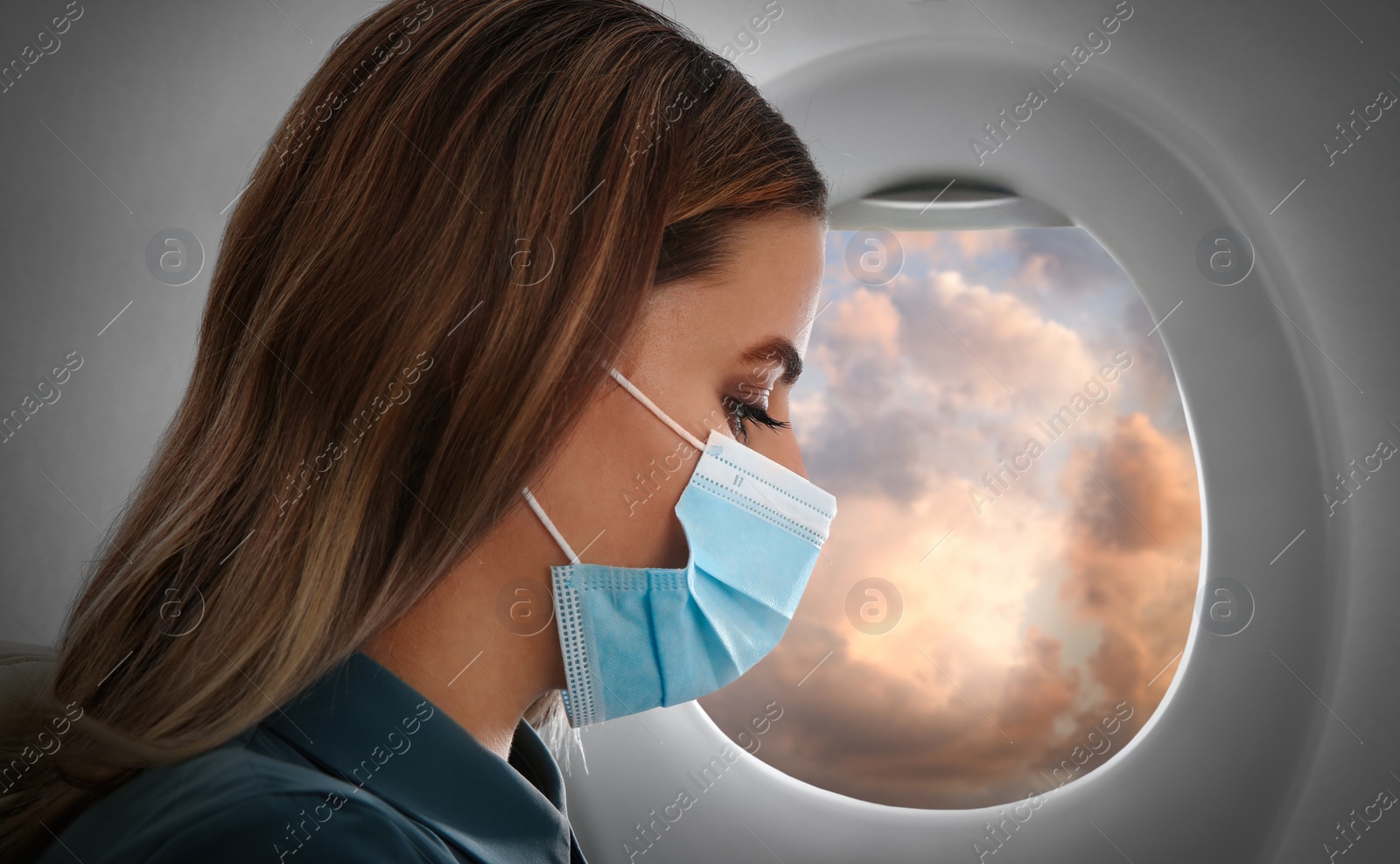 Image of Traveling by airplane during coronavirus pandemic. Woman with face mask near porthole