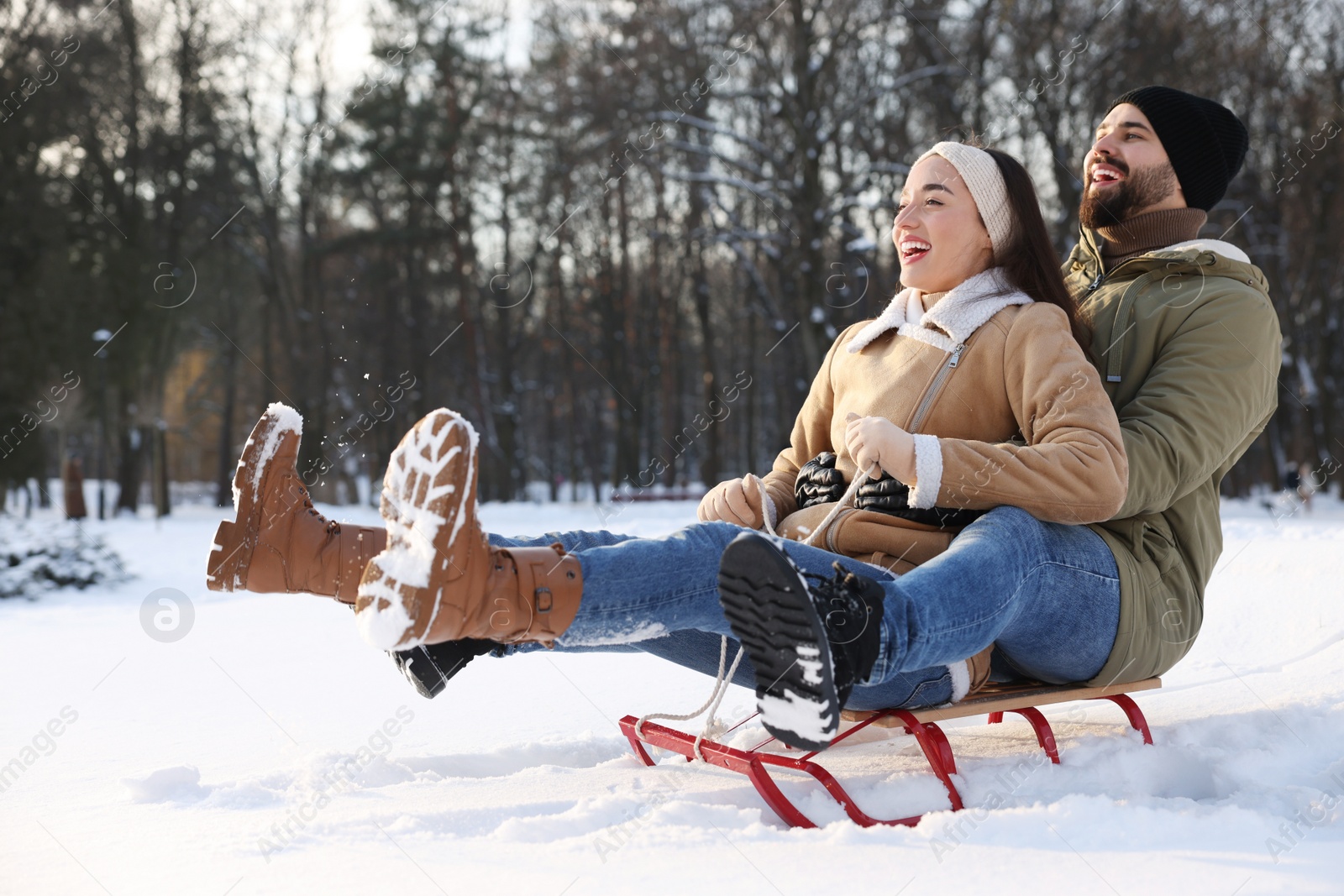 Photo of Happy young couple sledding outdoors on winter day