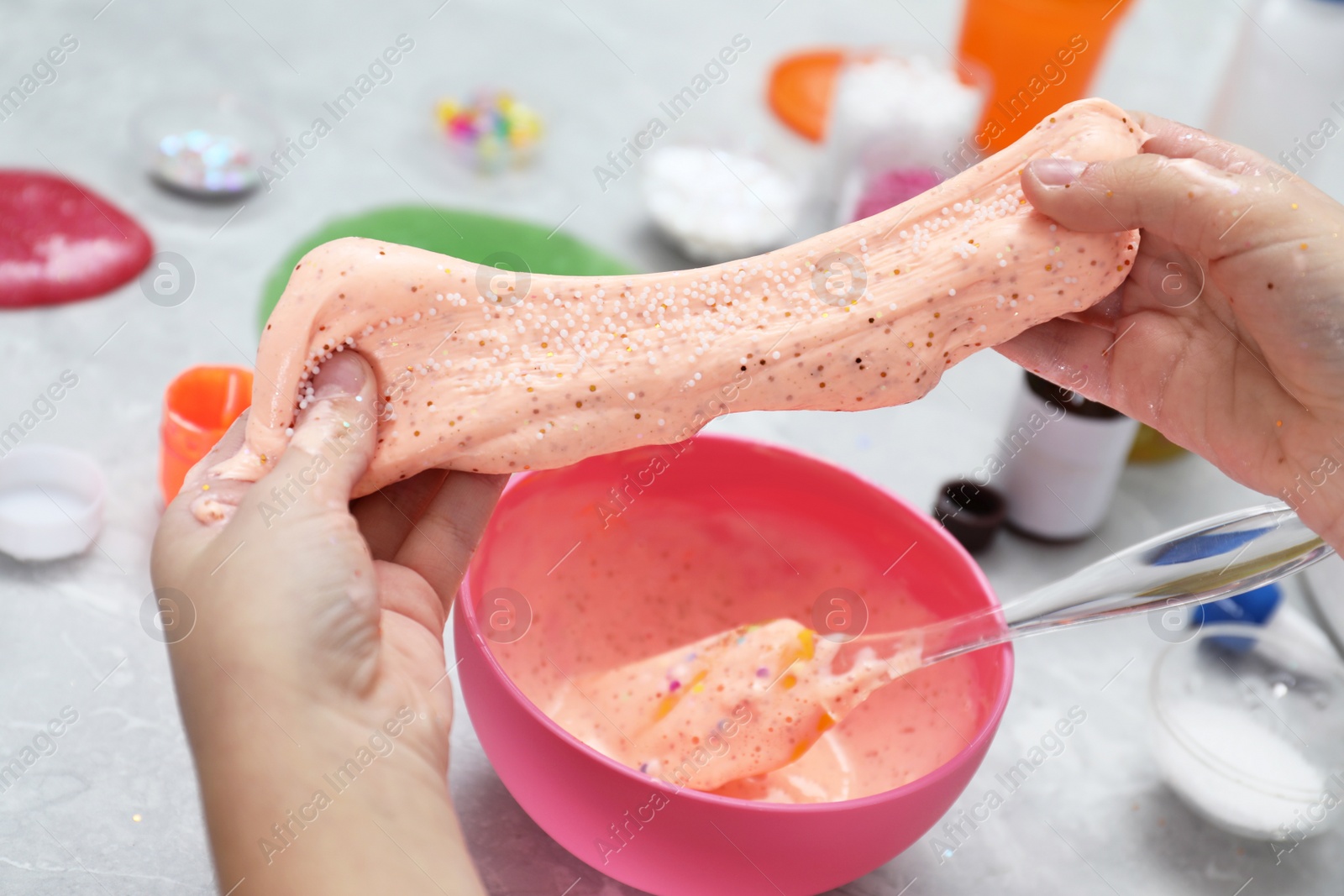 Photo of Little girl making DIY slime toy at table, closeup