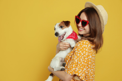 Young woman with her cute Jack Russell Terrier on yellow background, space for text. Lovely pet