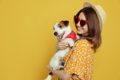 Photo of Young woman with her cute Jack Russell Terrier on yellow background, space for text. Lovely pet