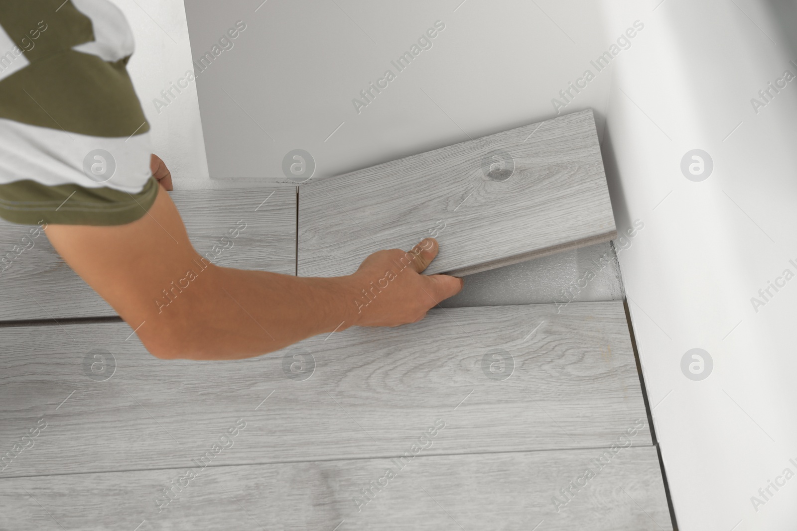 Photo of Professional worker installing new laminate flooring indoors, closeup