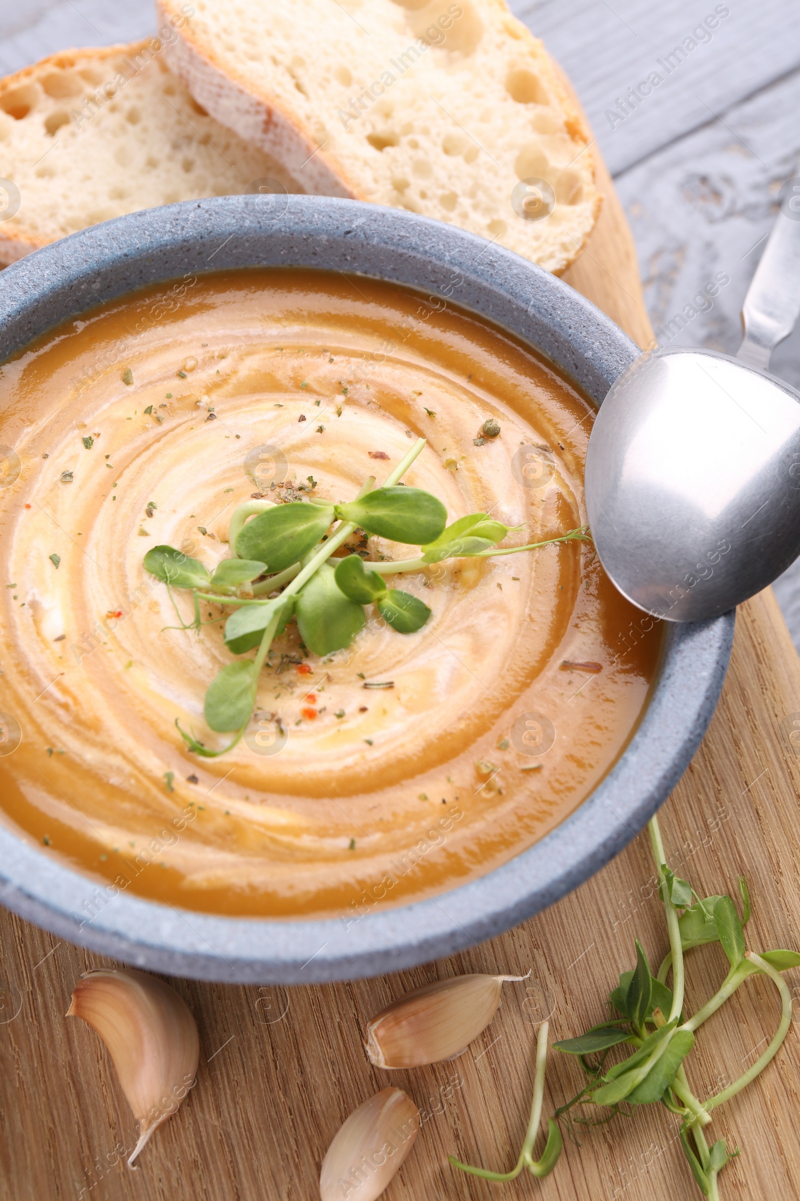 Photo of Tasty pumpkin soup with microgreens served on table, closeup