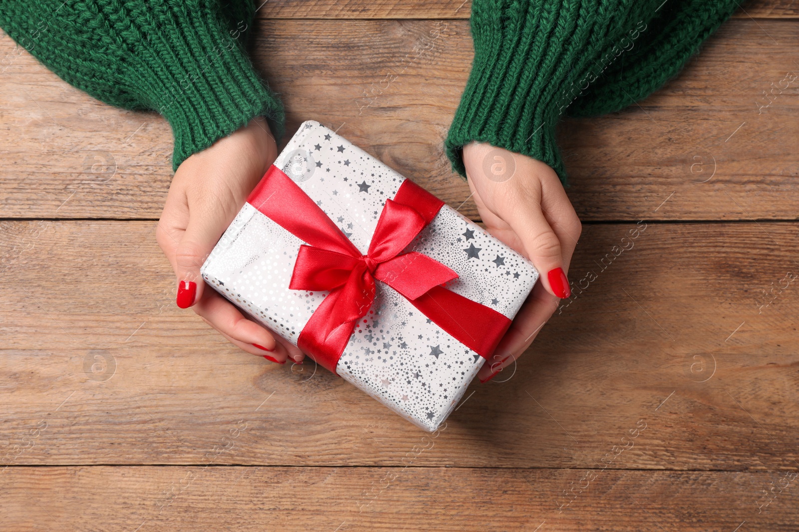 Photo of Christmas present. Woman with gift box at wooden table, top view