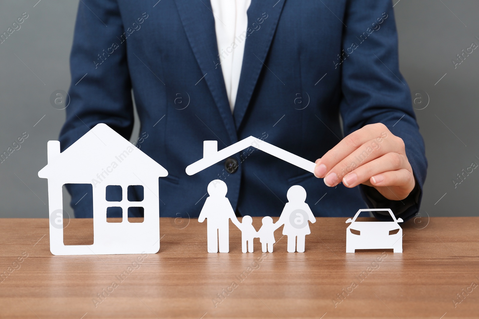 Photo of Woman with cutout paper family, house and car at table, closeup. Life insurance concept