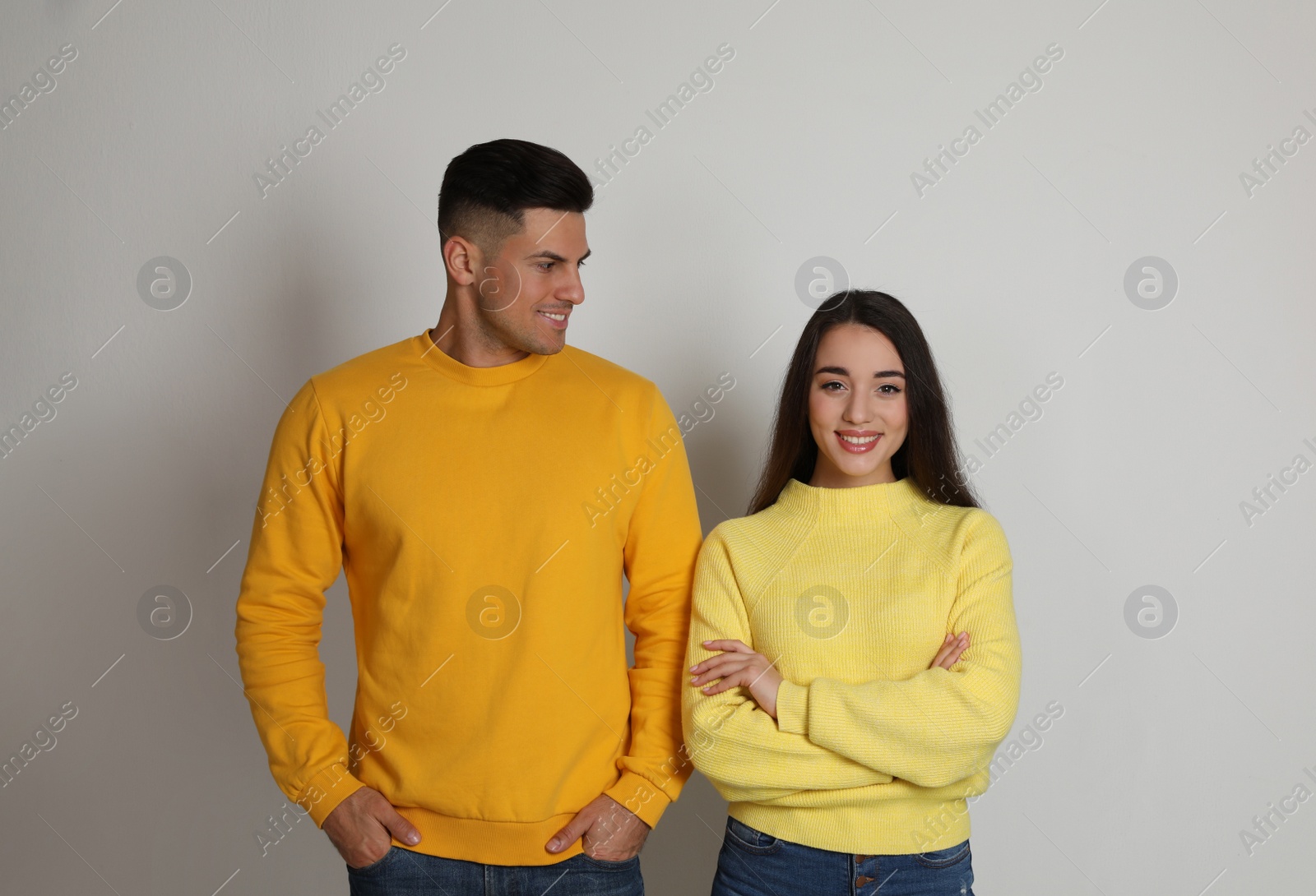 Photo of Happy couple wearing yellow warm sweaters on white background