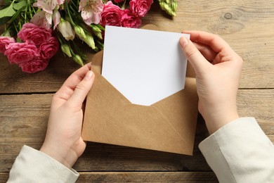 Photo of Happy Mother's Day. Woman holding envelope with blank card at wooden table, top view