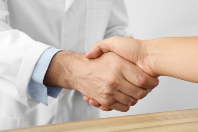 Photo of Doctor shaking hands with patient in hospital, closeup