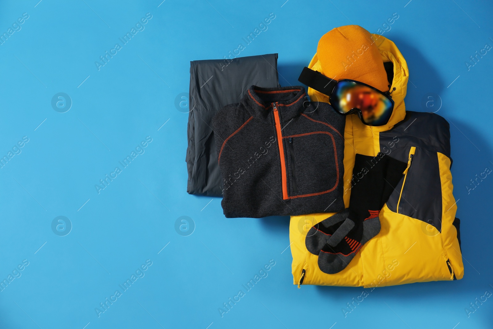 Photo of Stylish winter sport clothes on light blue background, flat lay. Space for text