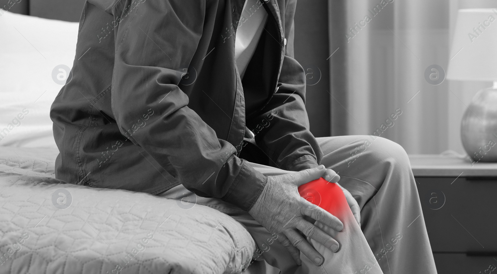 Image of Man suffering from pain in knee on bed at home, closeup. Black and white effect. Banner design