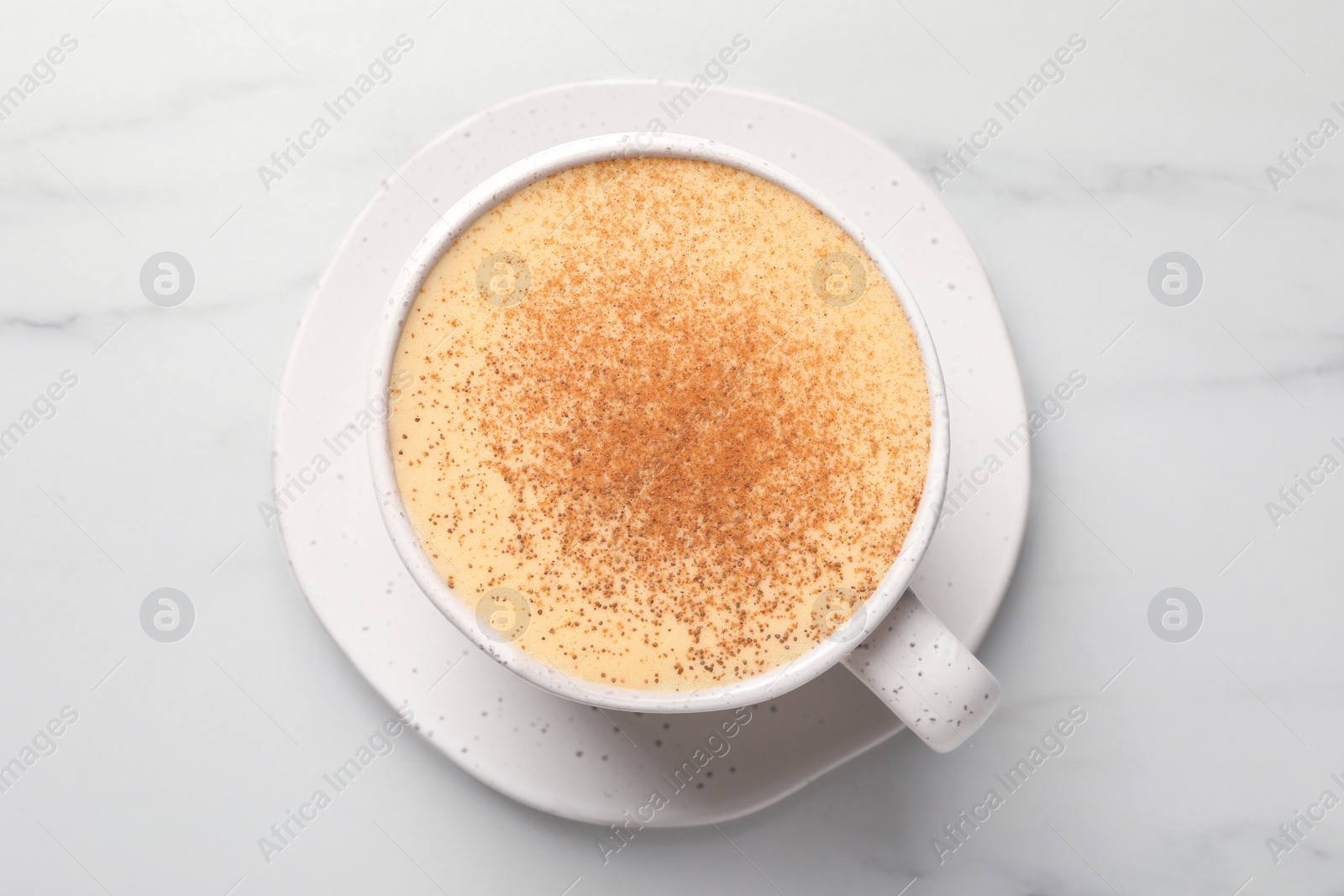 Photo of Delicious eggnog with cinnamon on white marble table, top view