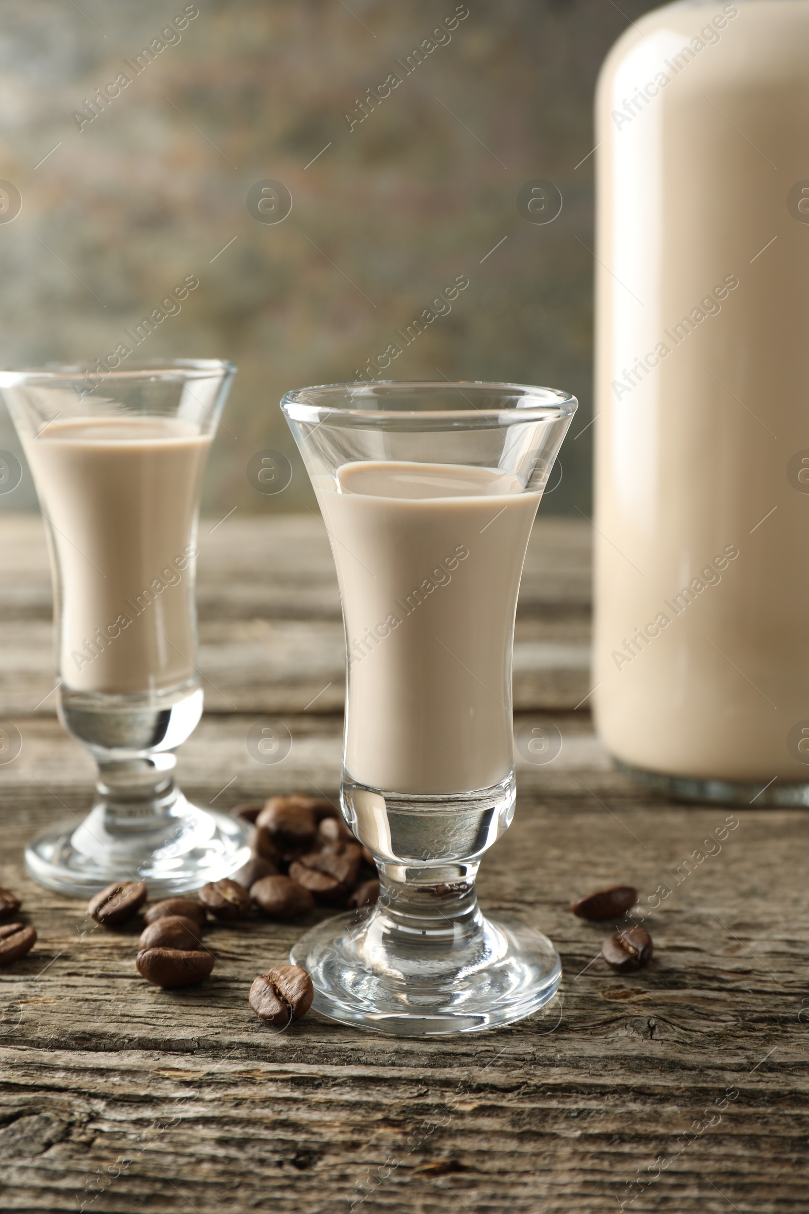 Photo of Coffee cream liqueur in glasses and beans on wooden table