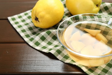 Delicious quince drink in glass bowl and fresh fruits on wooden table, closeup