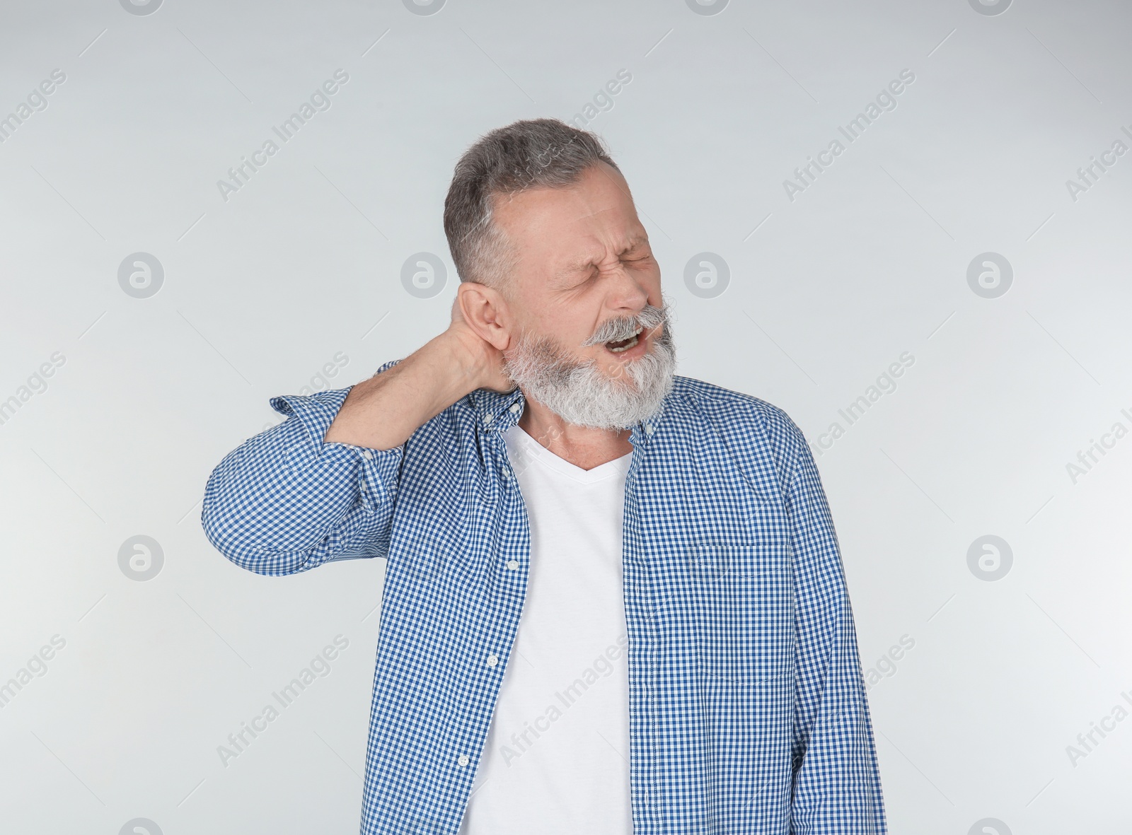 Photo of Man suffering from neck pain on light background