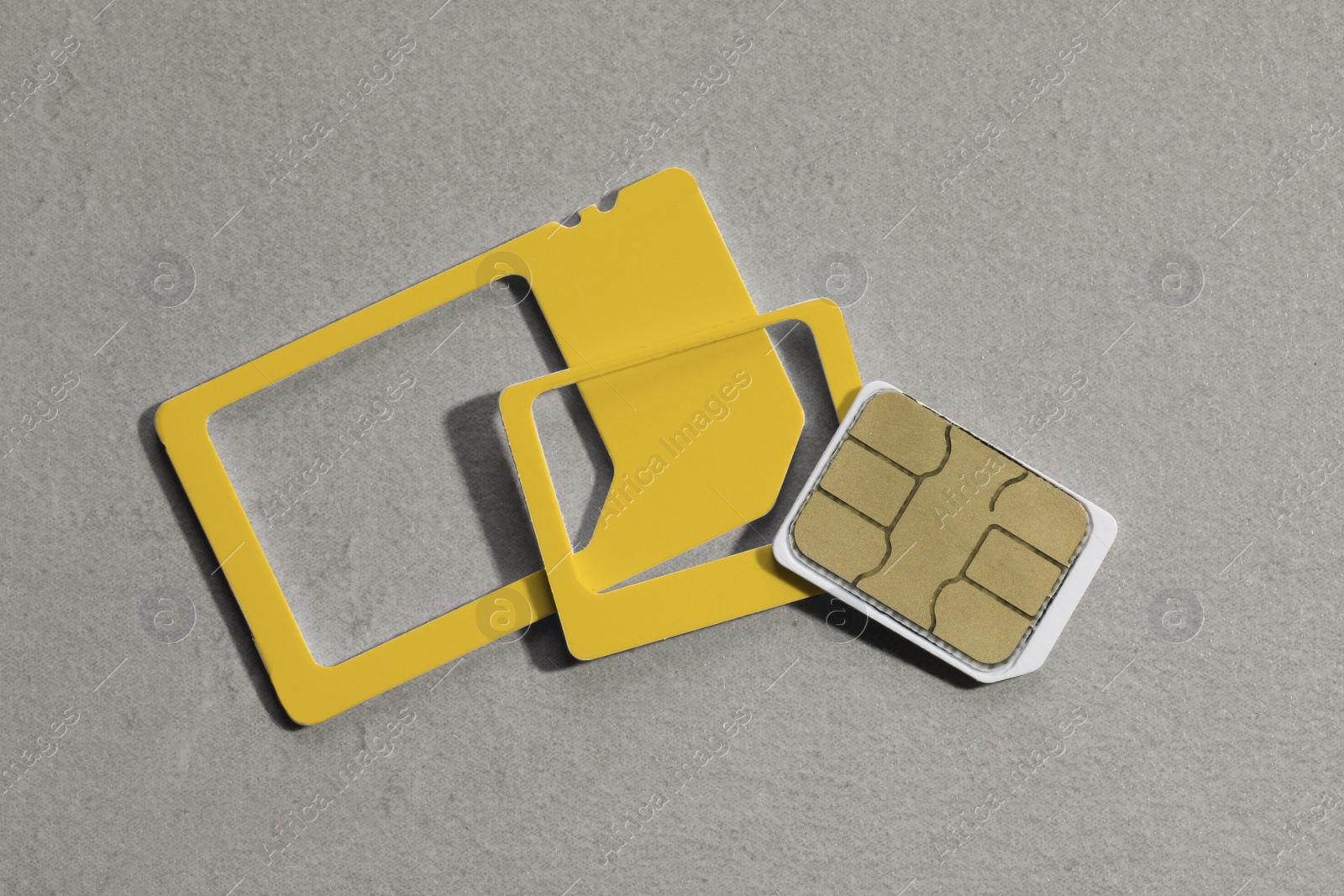 Photo of Multi SIM card on light grey stone background, flat lay