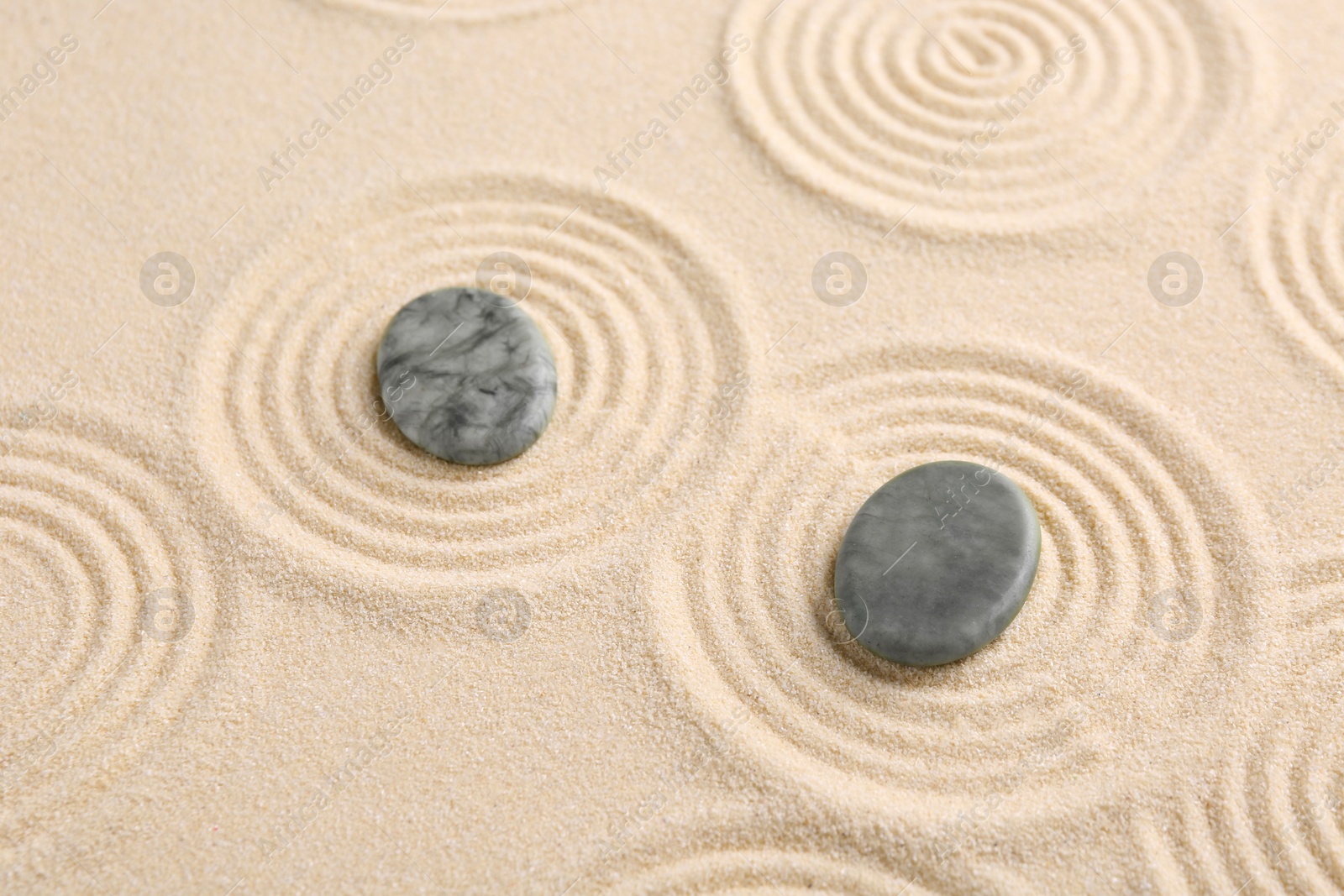 Photo of Zen garden stones on beige sand with pattern