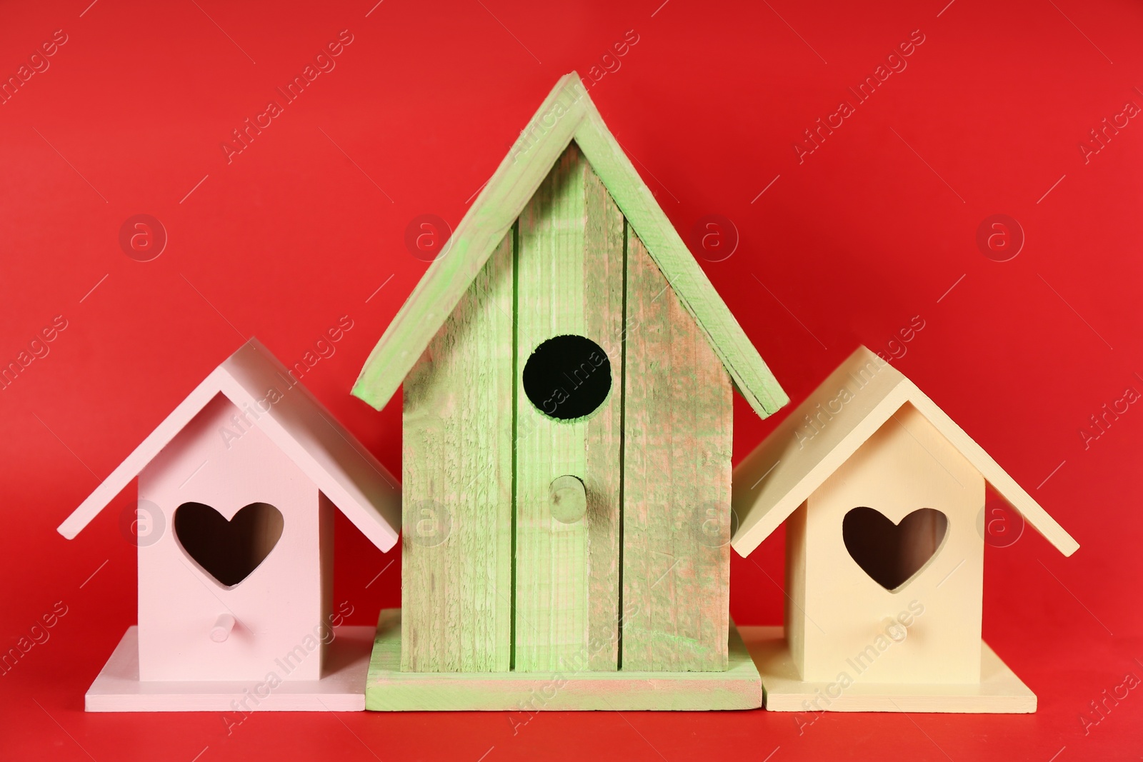 Photo of Beautiful wooden bird houses on red background