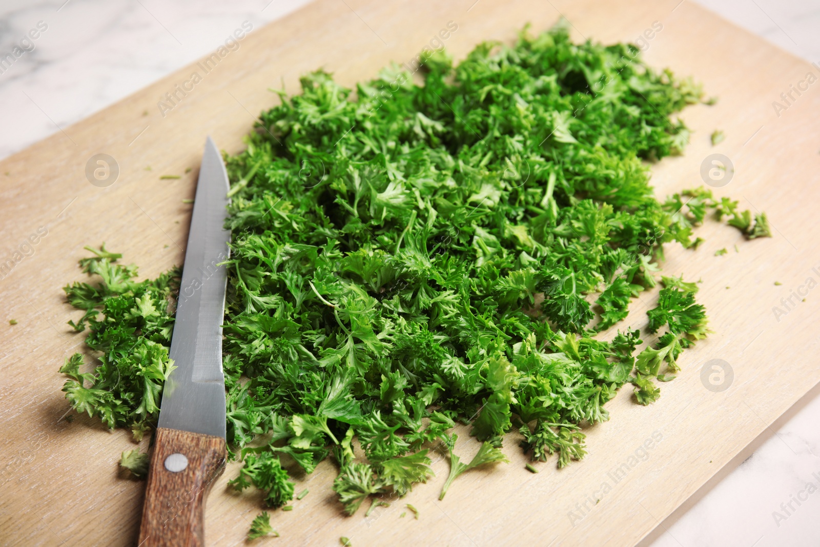 Photo of Wooden board with chopped parsley and knife on table, closeup