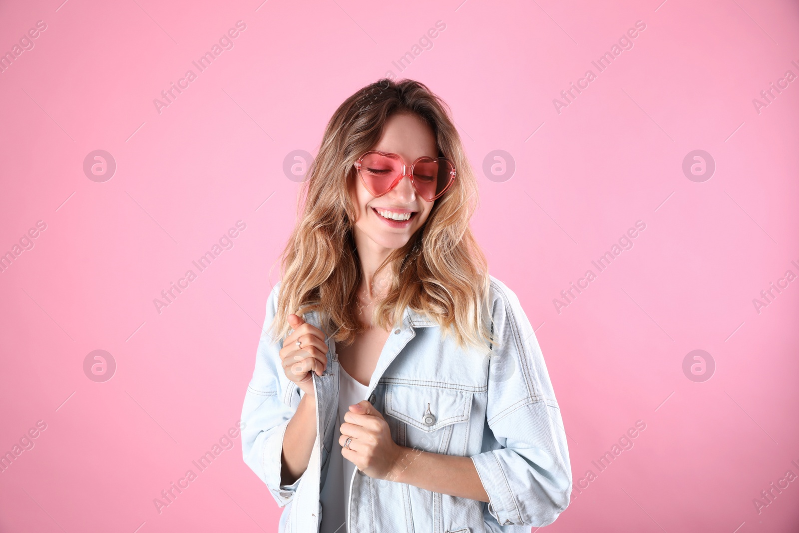 Photo of Young beautiful woman wearing heart shaped glasses on pink background