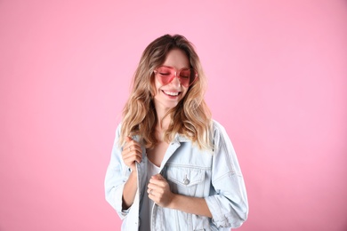 Photo of Young beautiful woman wearing heart shaped glasses on pink background