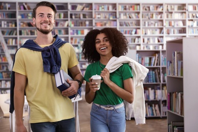 Photo of Happy young people with books in library