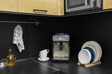 Coffee machine and kitchen utensils on black countertop