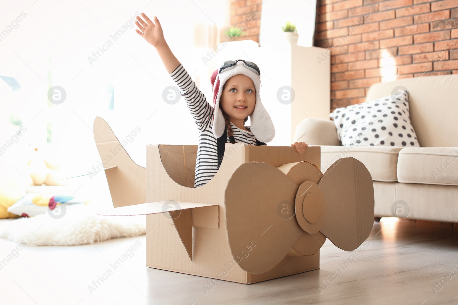 Photo of Adorable little child playing with cardboard plane at home