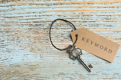 Photo of Key with tag KEYWORD on blue wooden background, top view. Space for text