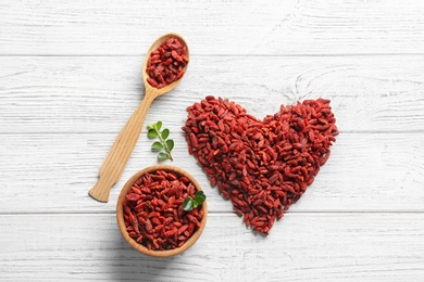 Photo of Flat lay composition with dried goji berries on white wooden table. Healthy superfood