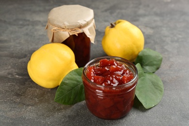 Photo of Delicious quince jam and fruits on grey table, closeup