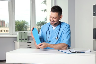 Handsome male orthopedist showing insole in hospital