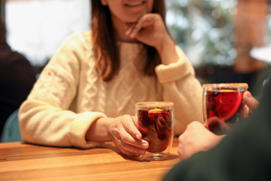 Photo of Lovely couple with tasty mulled wine at table in cafe, closeup