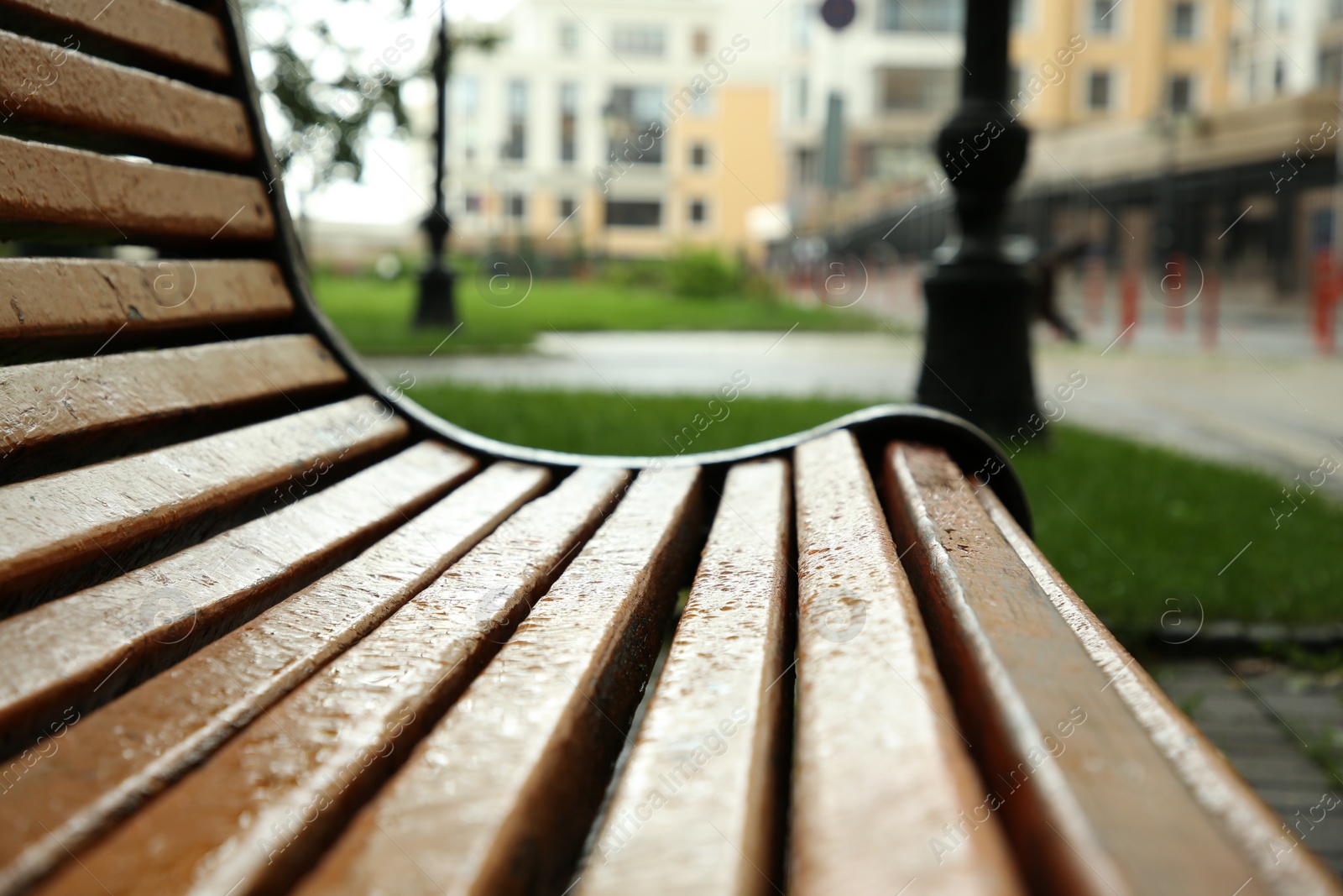 Photo of Wooden bench with water drops outdoors, closeup. Rainy weather