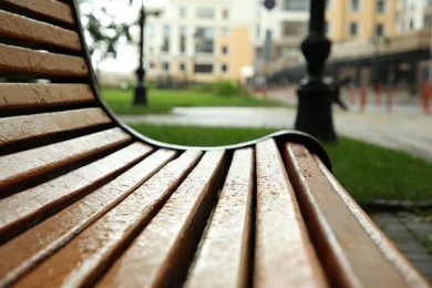 Photo of Wooden bench with water drops outdoors, closeup. Rainy weather