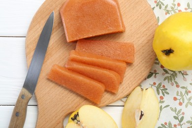 Tasty sweet quince paste, fresh fruits and knife on white wooden table, flat lay