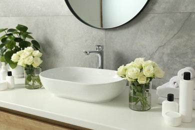 Photo of Beautiful roses and bath accessories near sink in bathroom