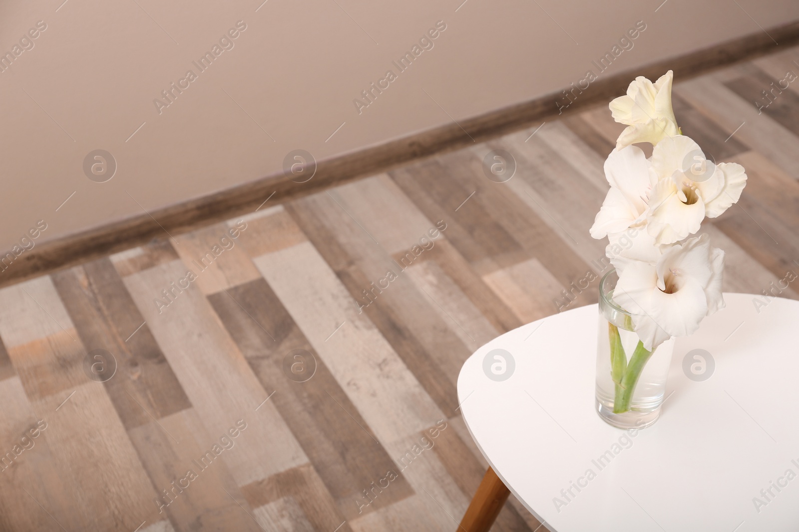 Photo of Vase with beautiful gladiolus flowers on wooden table indoors. Space for text