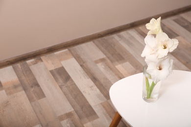 Vase with beautiful gladiolus flowers on wooden table indoors. Space for text