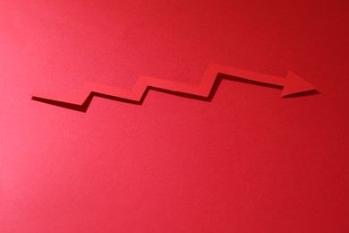 Photo of One zigzag paper arrow on red background. Space for text