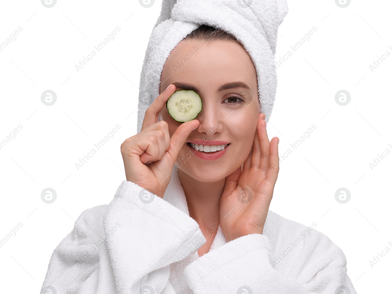 Photo of Beautiful woman in bathrobe covering eye with piece of cucumber on white background