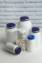 Medical bottles with pills on white wooden table