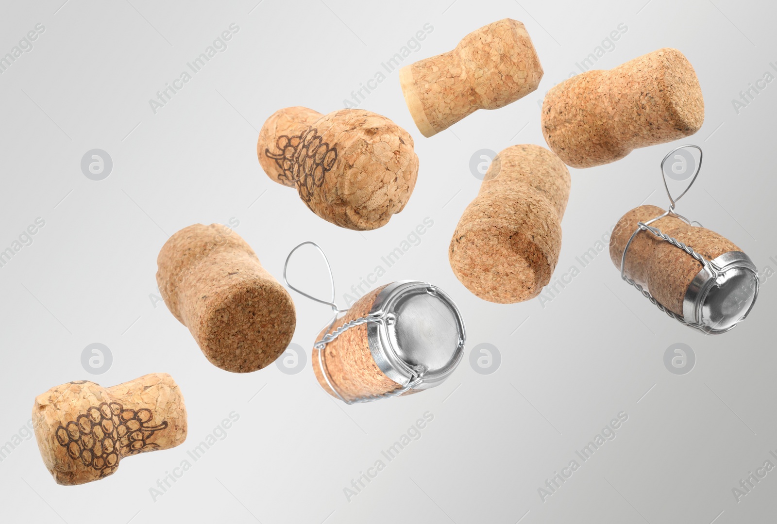 Image of Many corks of sparkling wine bottles falling on light grey background